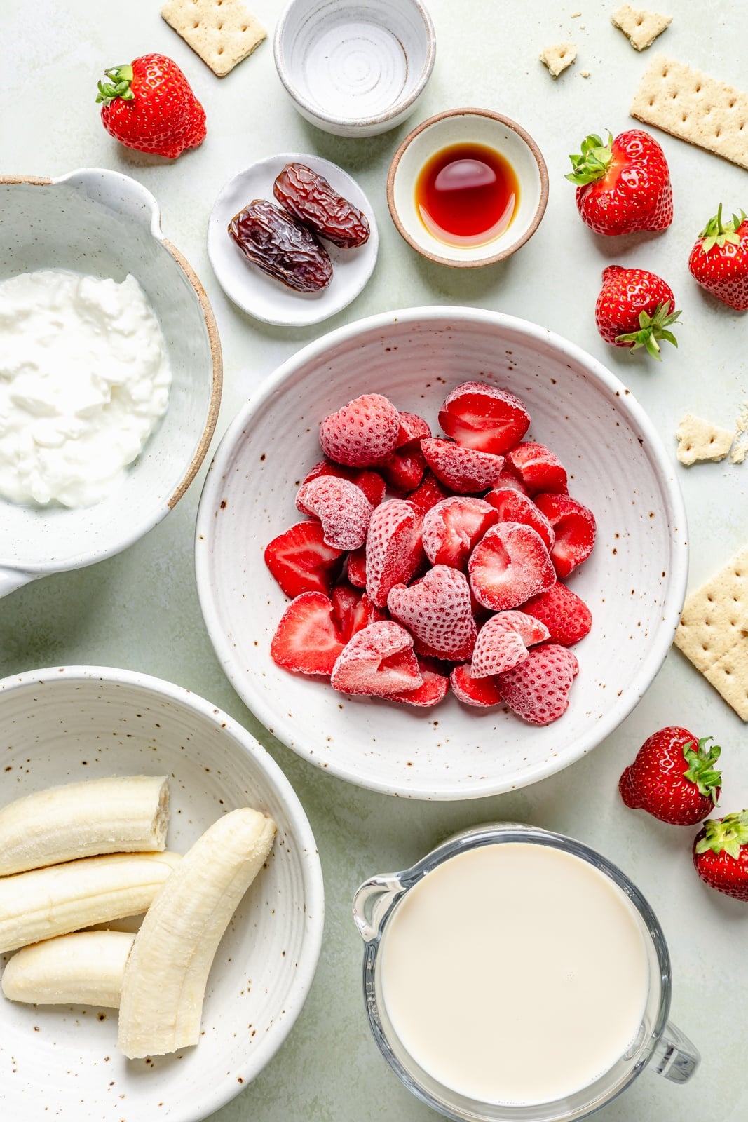 Sweet and tangy strawberry cheesecake smoothie packed with fiber and over 15g of protein from cottage cheese! This easy smoothie is made with just 6 simple ingredients for the perfect breakfast or snack that seriously tastes like dessert. ingredients for a healthy strawberry cheesecake smoothie in bowls