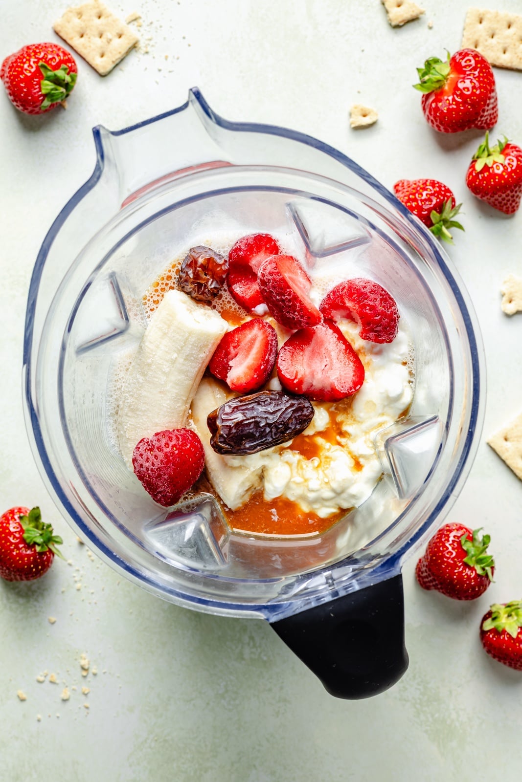 Sweet and tangy strawberry cheesecake smoothie packed with fiber and over 15g of protein from cottage cheese! This easy smoothie is made with just 6 simple ingredients for the perfect breakfast or snack that seriously tastes like dessert. ingredients for a high-protein strawberry cheesecake smoothie in a blender