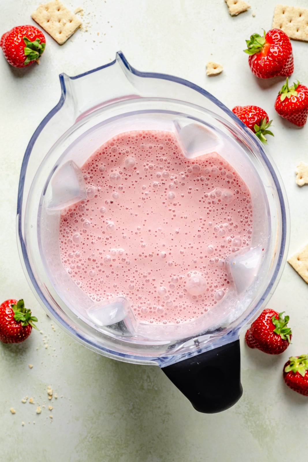 Sweet and tangy strawberry cheesecake smoothie packed with fiber and over 15g of protein from cottage cheese! This easy smoothie is made with just 6 simple ingredients for the perfect breakfast or snack that seriously tastes like dessert. top-down view of a strawberry cheesecake smoothie in a blender