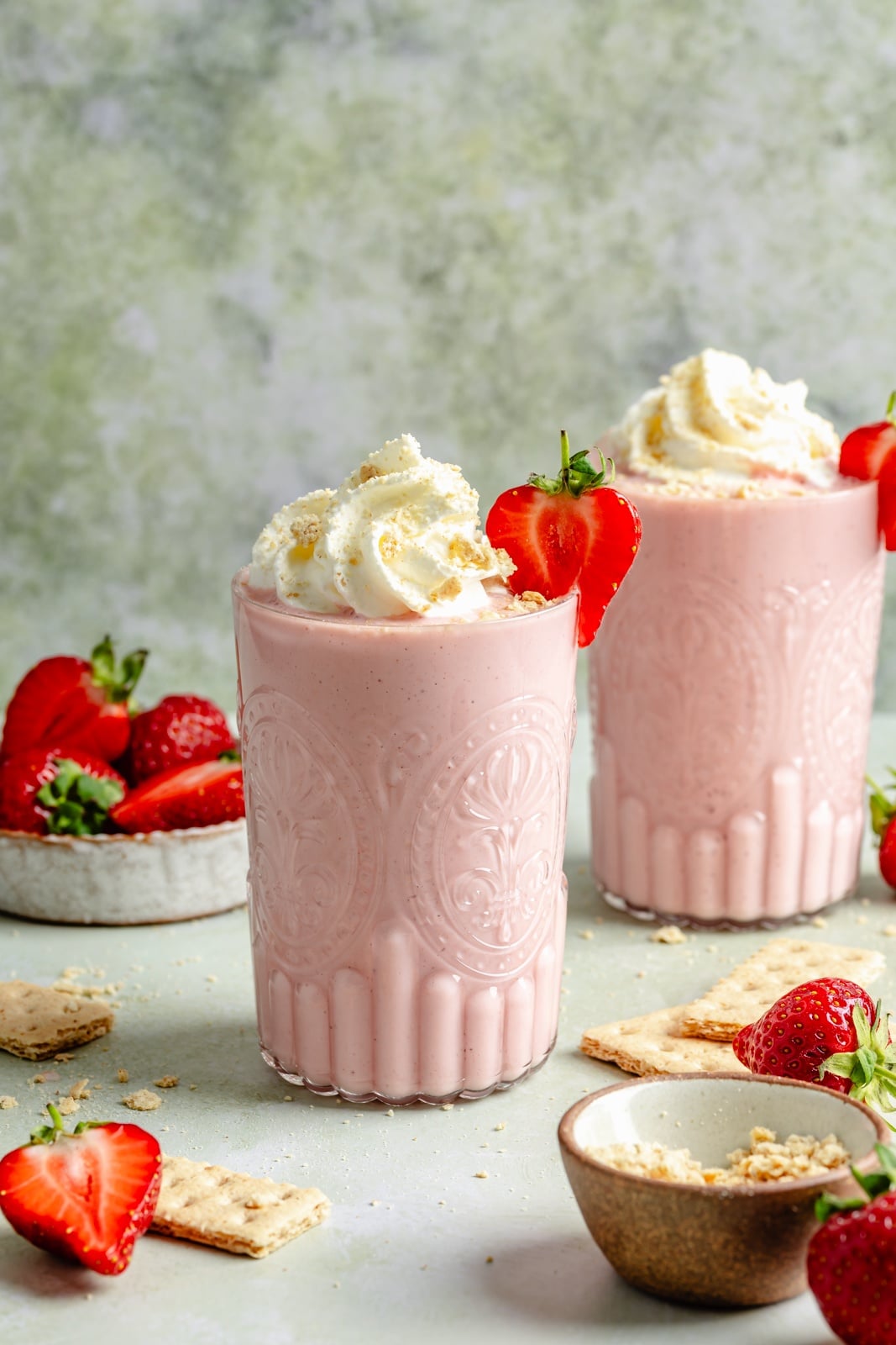 Sweet and tangy strawberry cheesecake smoothie packed with fiber and over 15g of protein from cottage cheese! This easy smoothie is made with just 6 simple ingredients for the perfect breakfast or snack that seriously tastes like dessert. strawberry cheesecake smoothie in two glasses topped with whipped cream