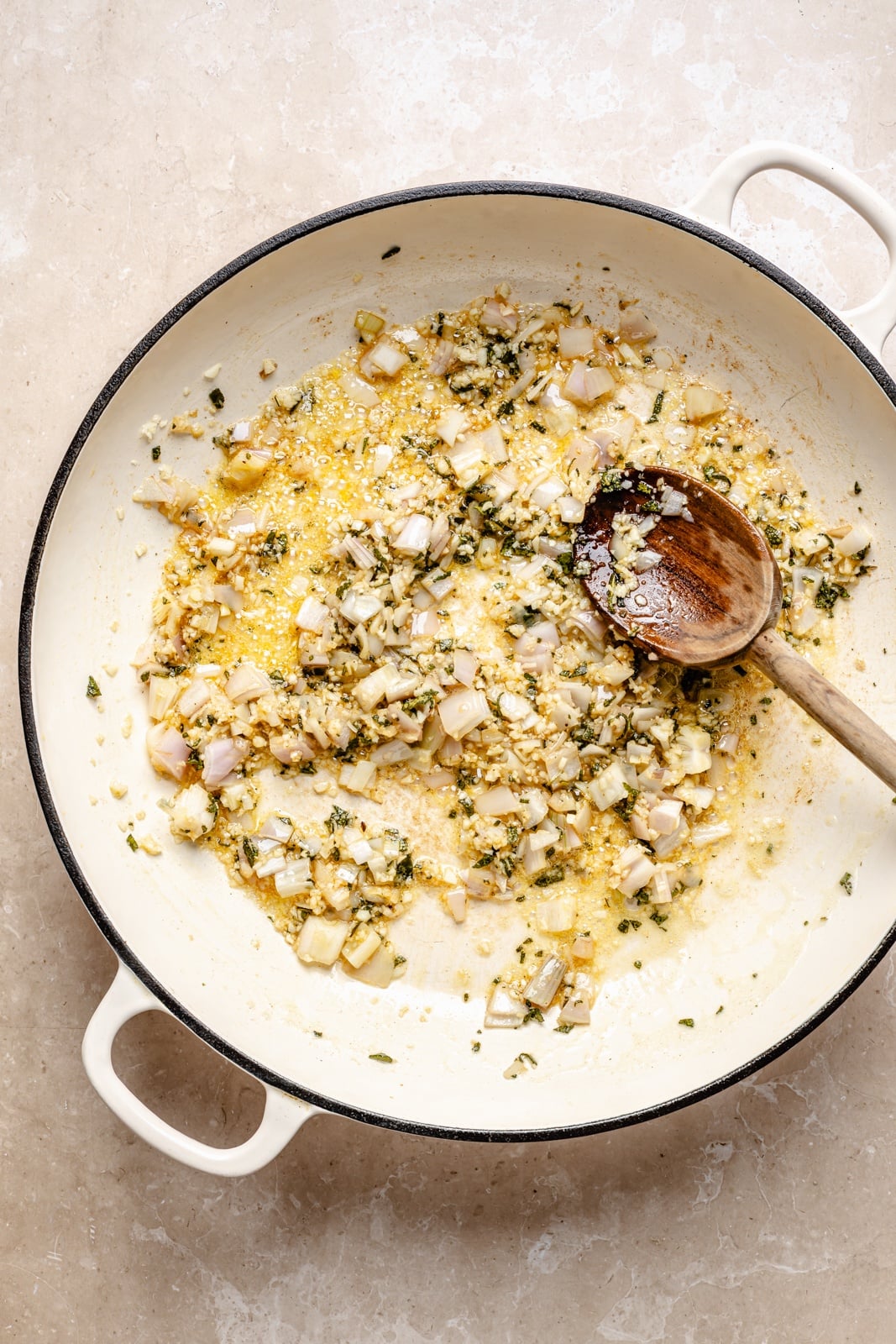 Creamy one pan brown butter sage orzo with spicy sausage, tender butternut squash, and tangy goat cheese. This sweet and savory orzo recipe is filled with cozy fall flavors, plus an extra boost of veggies from spinach! A beautiful weeknight dinner the whole family will love. cooking down sage, garlic, and a shallot in a pot