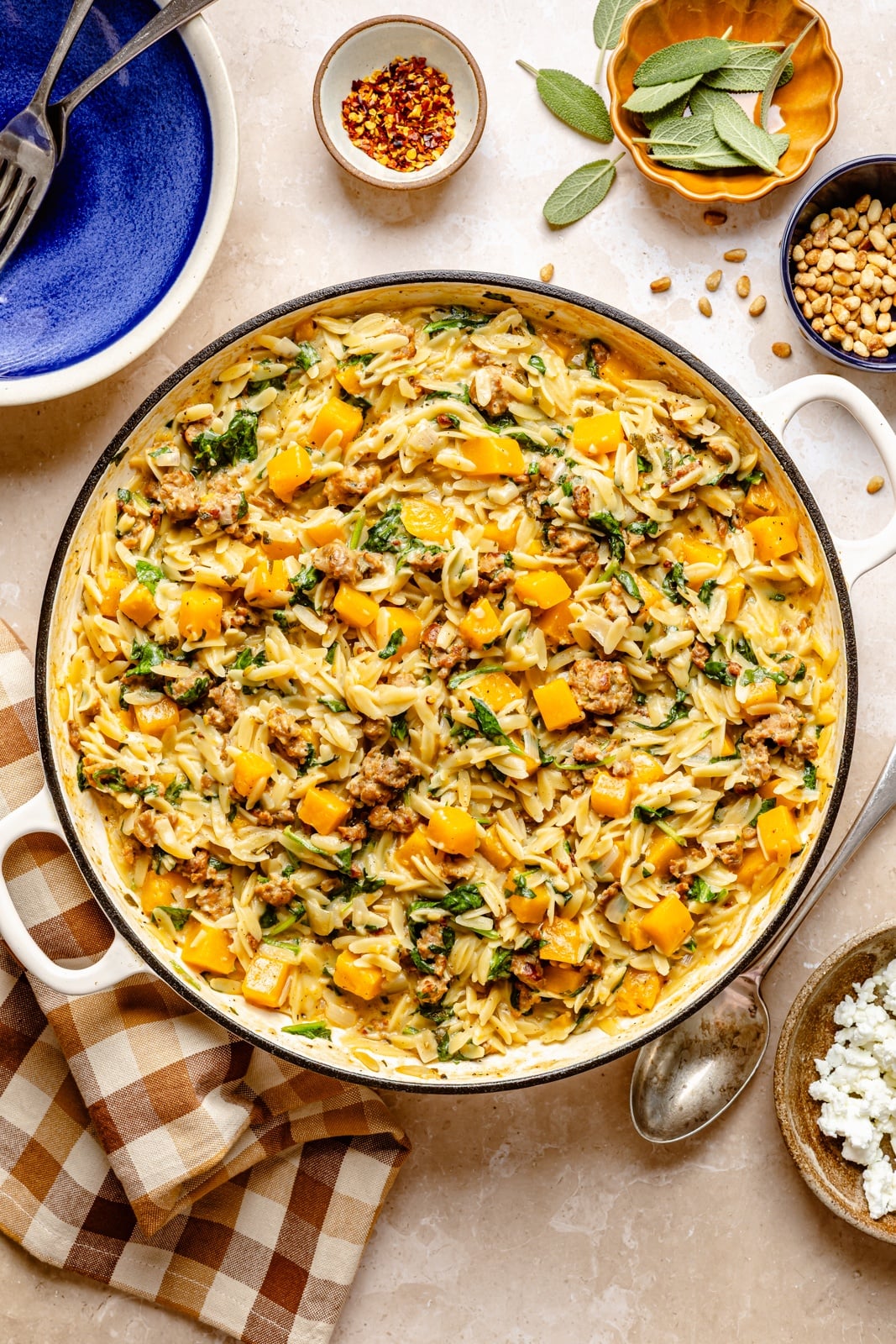 Creamy one pan butternut squash orzo with rich, sage-infused brown butter, spicy sausage, and tangy goat cheese. This sweet and savory orzo recipe is filled with cozy fall flavors, plus an extra boost of veggies from spinach! A beautiful weeknight dinner the whole family will love. brown butter butternut squash orzo with sausage in a pan