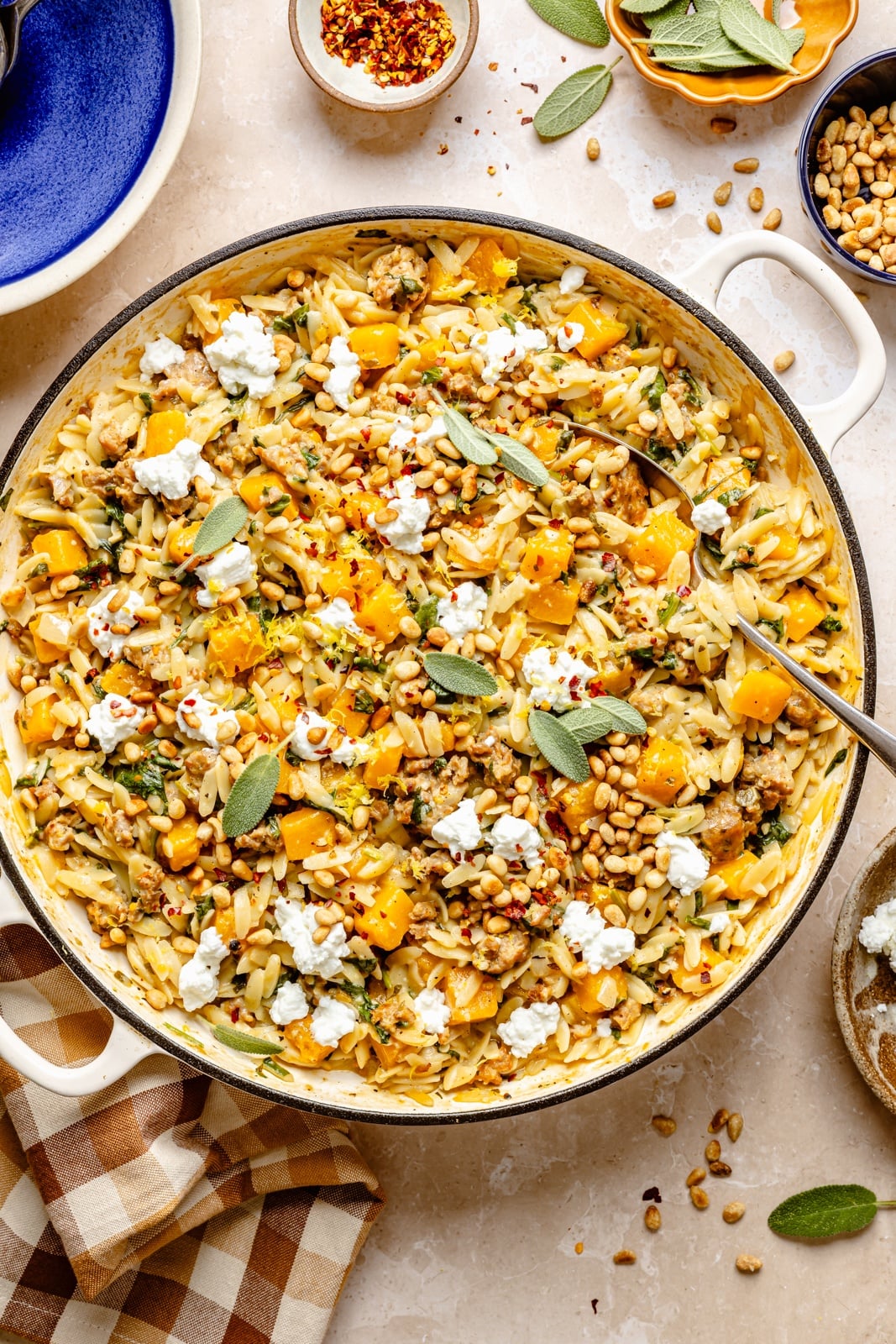 Creamy one pan butternut squash orzo with rich, sage-infused brown butter, spicy sausage, and tangy goat cheese. This sweet and savory orzo recipe is filled with cozy fall flavors, plus an extra boost of veggies from spinach! A beautiful weeknight dinner the whole family will love. brown butter sage orzo with butternut squash and sausage in a pot