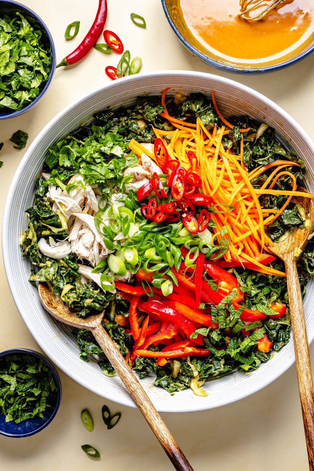 The ultimate crunchy peanut kale salad packed with a rainbow of vegetables and herbs, tossed in a dreamy, creamy ginger peanut dressing. This beautiful kale salad stays good in the fridge for days, making it the perfect high-fiber, protein-packed meal prep lunch! Enjoy as is or add an extra boost of protein for a heartier meal. unmixed peanut kale salad in a mixing bowl