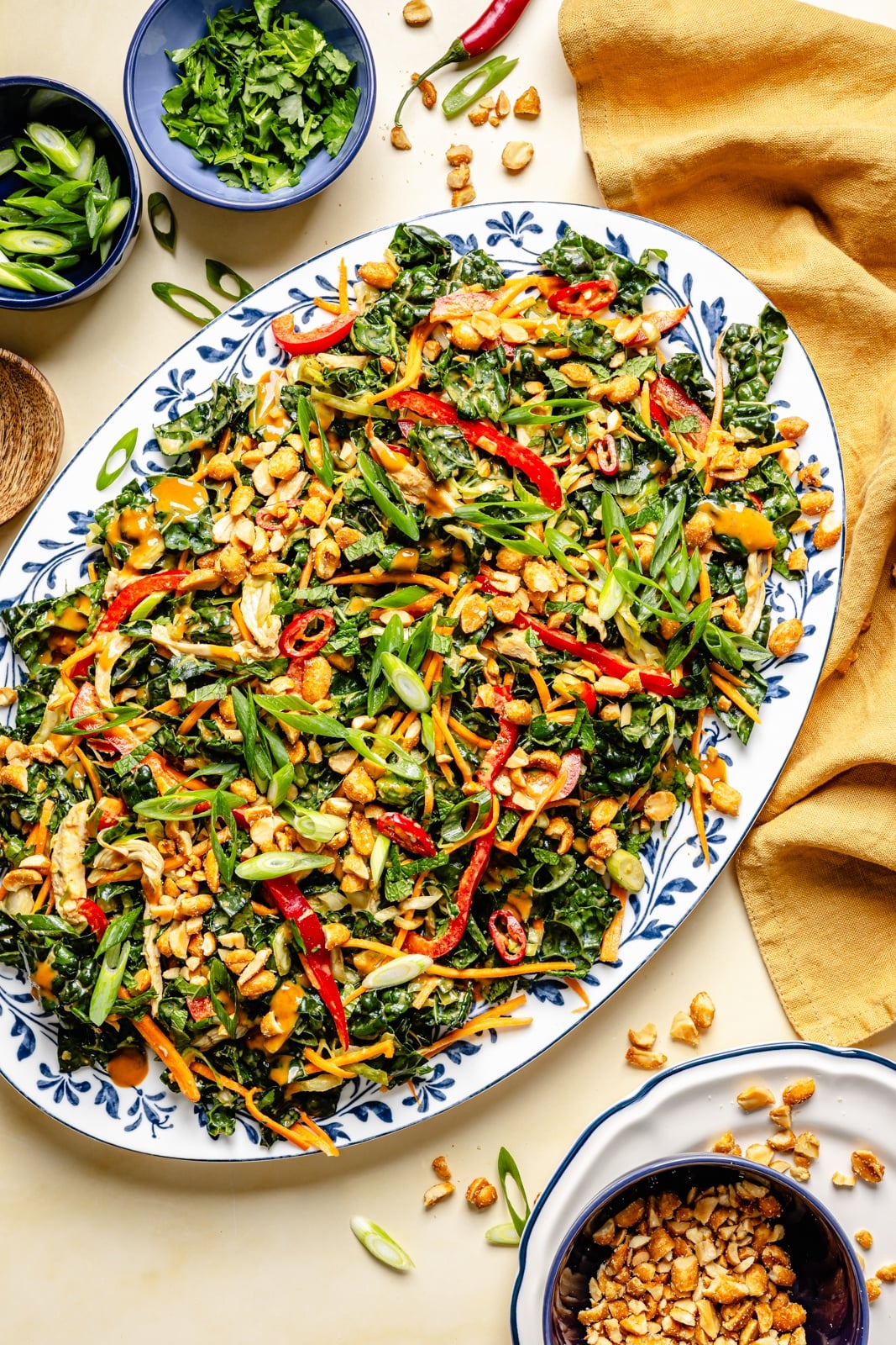 The ultimate crunchy peanut kale salad packed with a rainbow of vegetables and herbs, tossed in a dreamy, creamy ginger peanut dressing. This beautiful kale salad stays good in the fridge for days, making it the perfect high-fiber, protein-packed meal prep lunch! Enjoy as is or add an extra boost of protein for a heartier meal. kale peanut salad on a platter