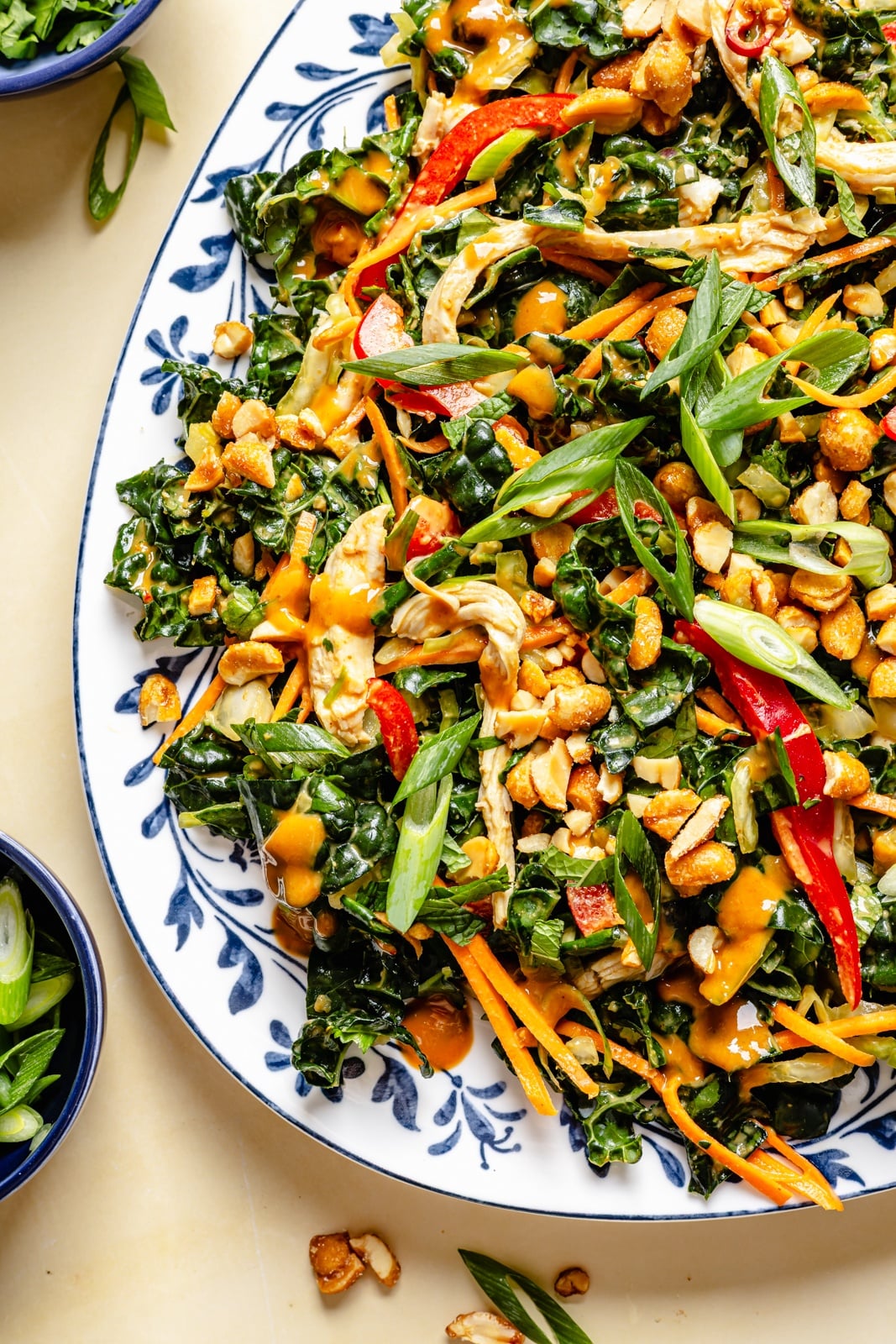 The ultimate crunchy peanut kale salad packed with a rainbow of vegetables and herbs, tossed in a dreamy, creamy ginger peanut dressing. This beautiful kale salad stays good in the fridge for days, making it the perfect high-fiber, protein-packed meal prep lunch! Enjoy as is or add an extra boost of protein for a heartier meal. healthy peanut kale crunch salad on a platter