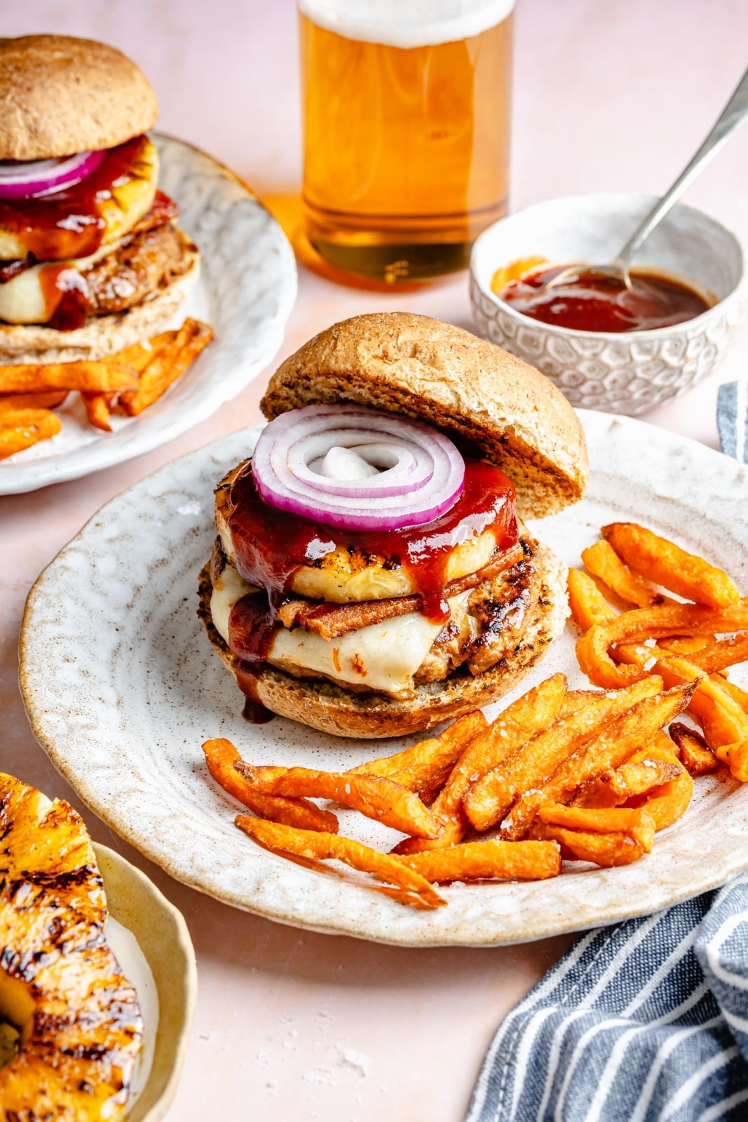 Flavorful, juicy BBQ bacon turkey burgers with a Hawaiian-inspired twist from a slice of sweet grilled pineapple. Use your favorite BBQ sauce, add a kick of heat from pepper jack cheese, and grill or pan-fry these burgers for the ultimate summer dinner! BBQ Hawaiian turkey burger on a plate with sweet potato fries