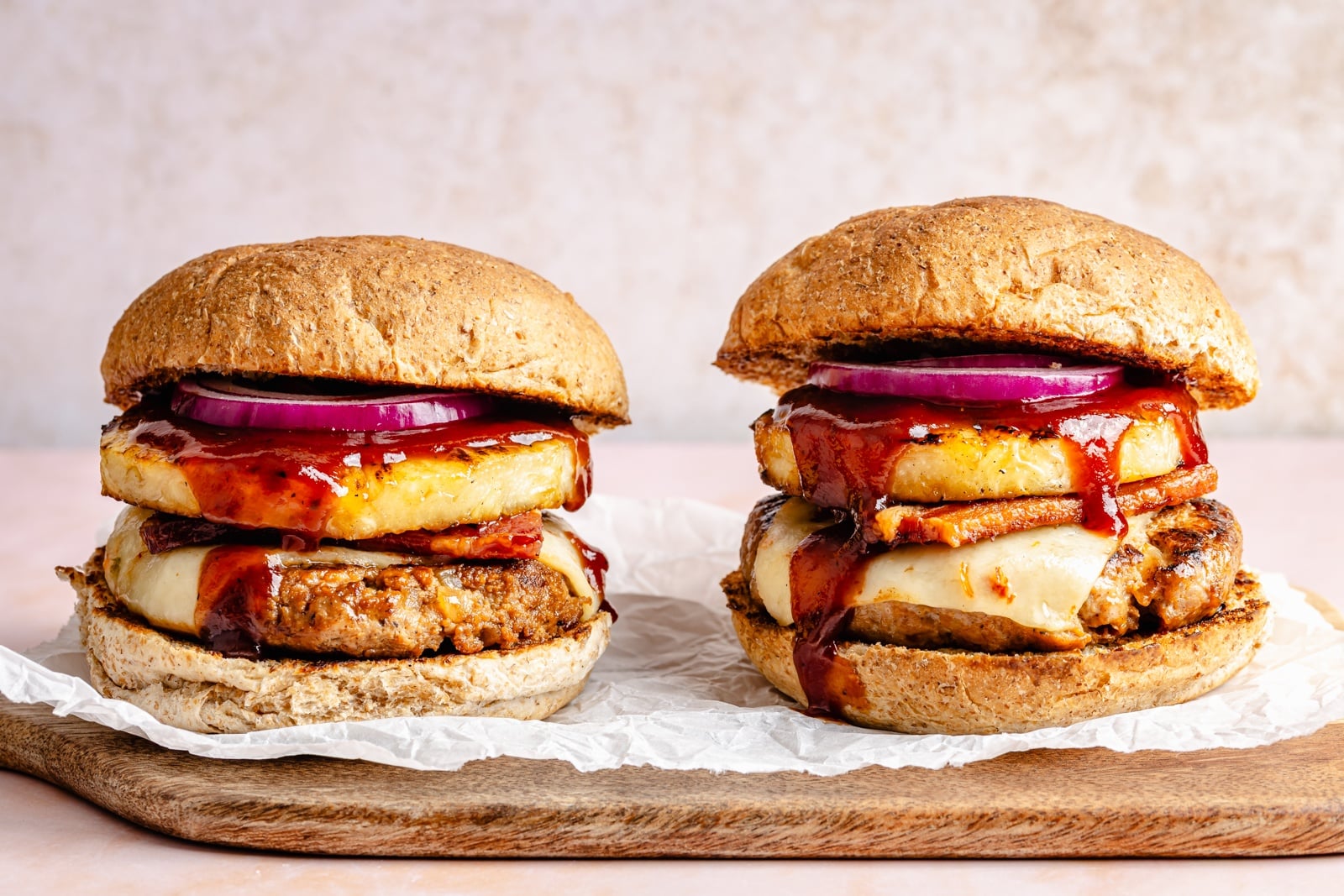 Flavorful, juicy BBQ bacon turkey burgers with a Hawaiian-inspired twist from a slice of sweet grilled pineapple. Use your favorite BBQ sauce, add a kick of heat from pepper jack cheese, and grill or pan-fry these burgers for the ultimate summer dinner! two BBQ bacon turkey burgers with pineapple on a wooden board
