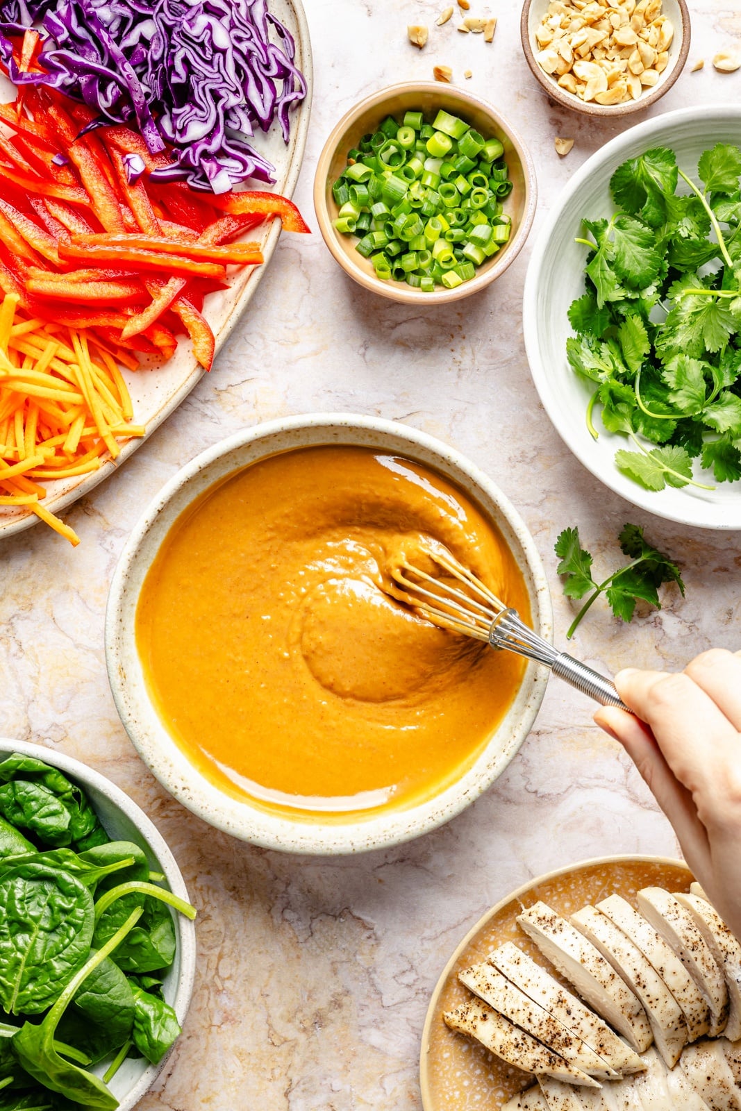 whisking dressing for thai peanut chicken wraps in a bowl
