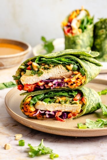 thai peanut chicken wrap stacked on a plate