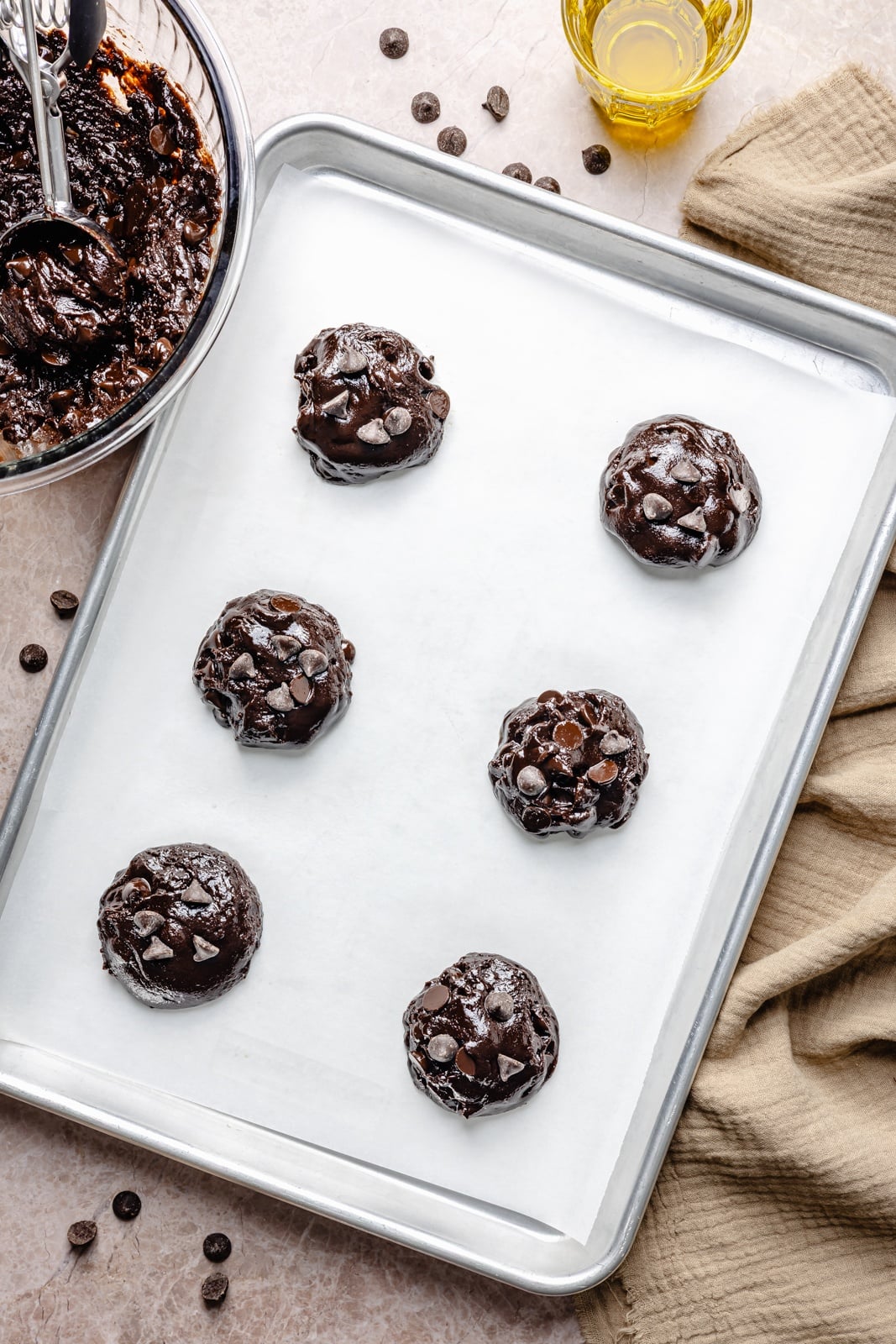 Fudgy double chocolate olive oil cookies with perfectly crisp edges and chewy centers. These incredible cookies take just 10 minutes to mix and 10 to bake, so you can have the ultimate chocolate lover's dessert in no time! Easily make them gluten-free, and add a sprinkle of sea salt for a sweet-salty combo. unbaked chocolate olive oil cookies on a baking sheet