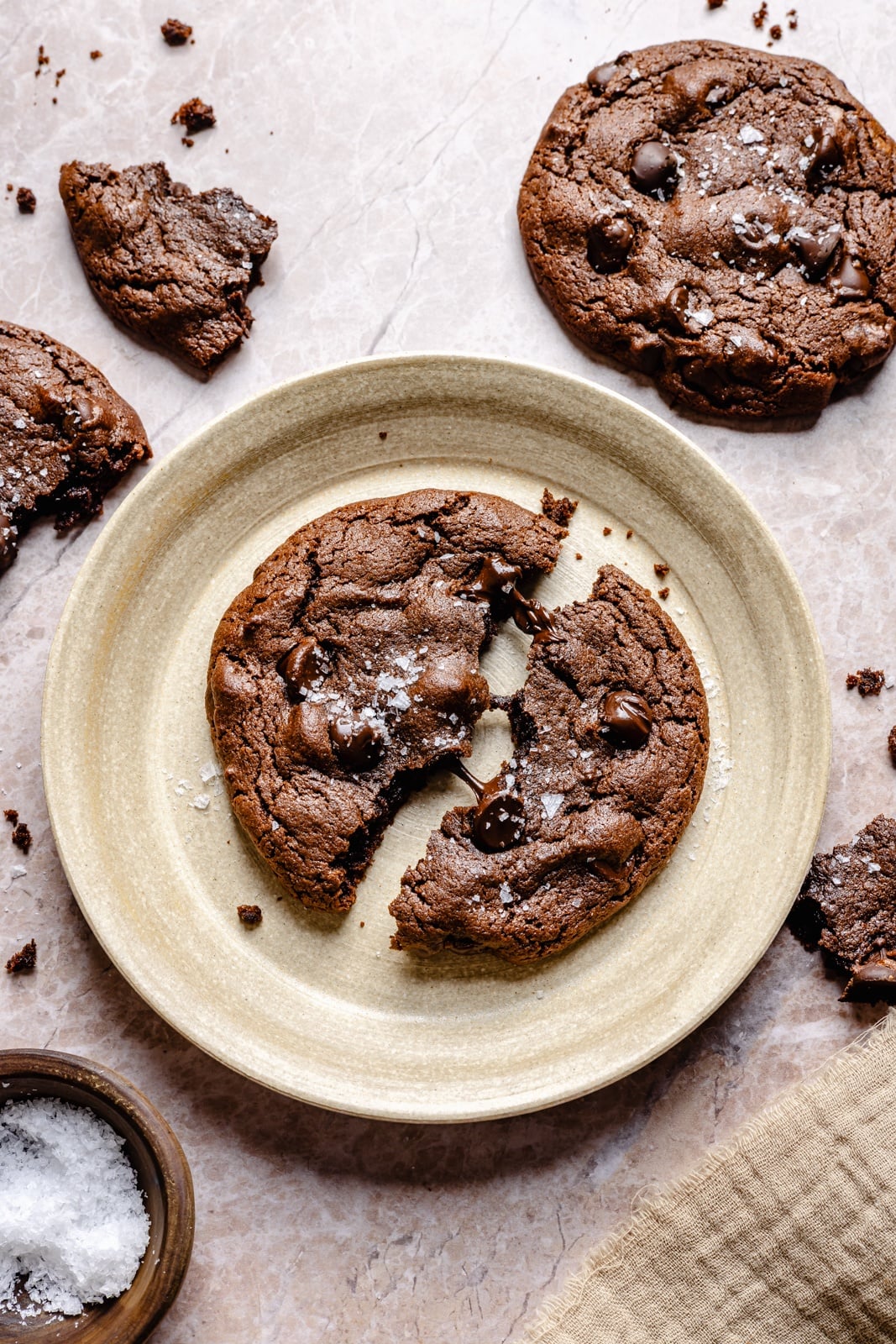 Fudgy double chocolate olive oil cookies with perfectly crisp edges and chewy centers. These incredible cookies take just 10 minutes to mix and 10 to bake, so you can have the ultimate chocolate lover's dessert in no time! Easily make them gluten-free, and add a sprinkle of sea salt for a sweet-salty combo. double chocolate olive oil cookie broken in half on a plate