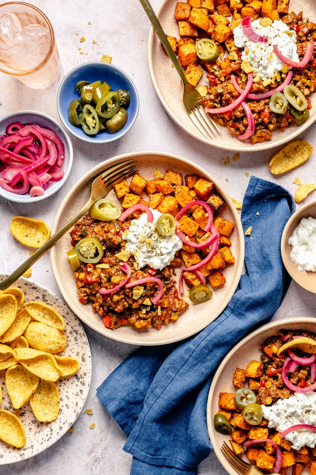 Easy, protein-packed sloppy joe bowls with spiced sweet potatoes, a sneaky rainbow of veggies, and delicious, savory toppings. Fuel your weekday with these nourishing meal prep bowls, and scoop them up with chips for a yummy crunch! three sloppy joe bowls with sweet potatoes and corn chips