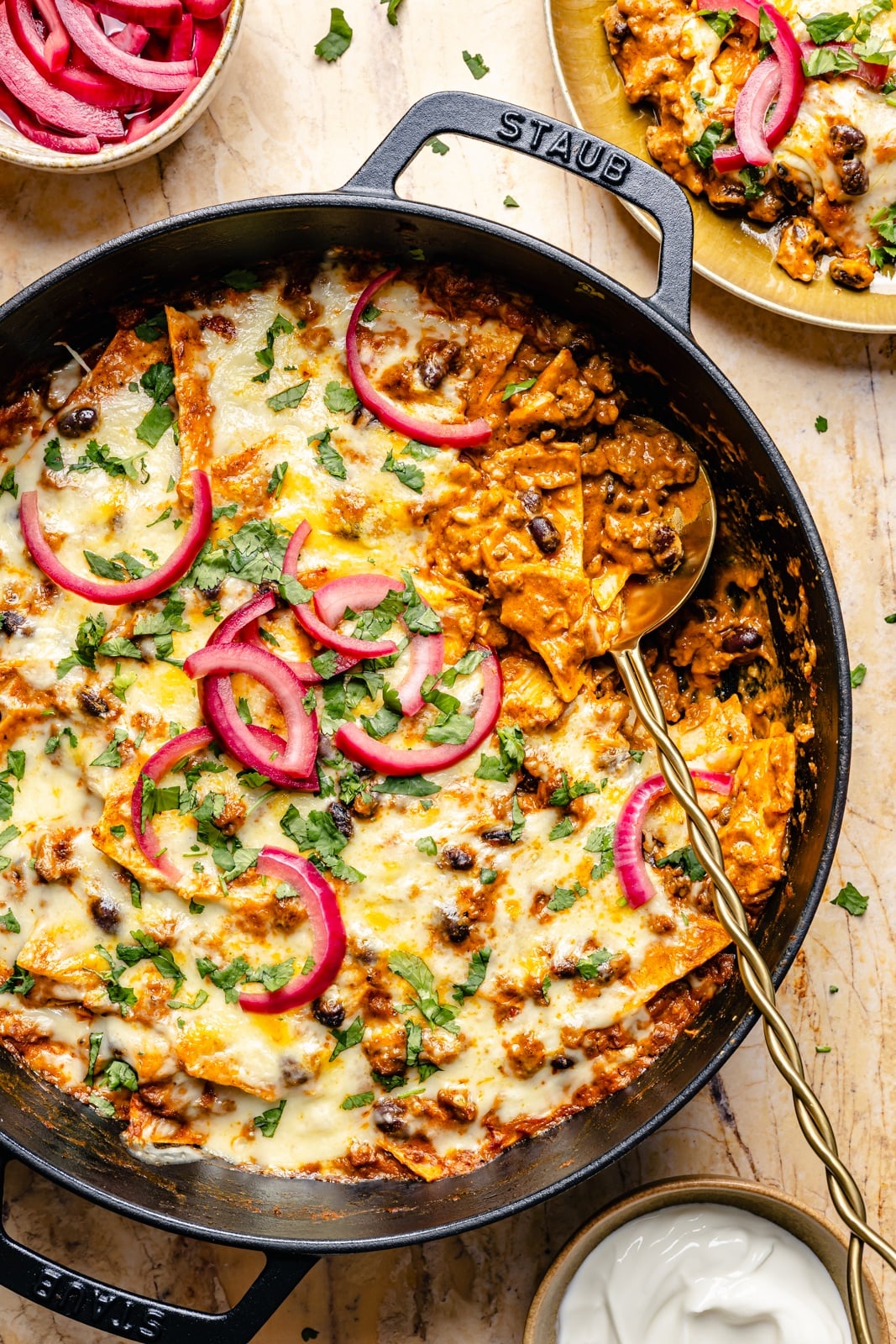 cheesy pumpkin and beef enchilada skillet in a pan with a metal spoon