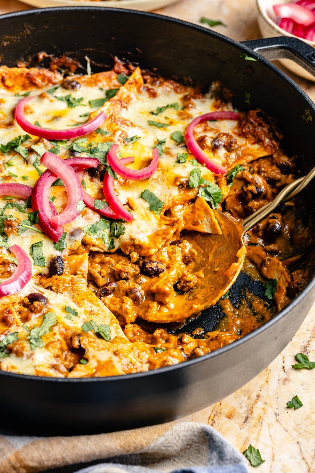 beef and pumpkin enchilada skillet in a pan with a metal spoon