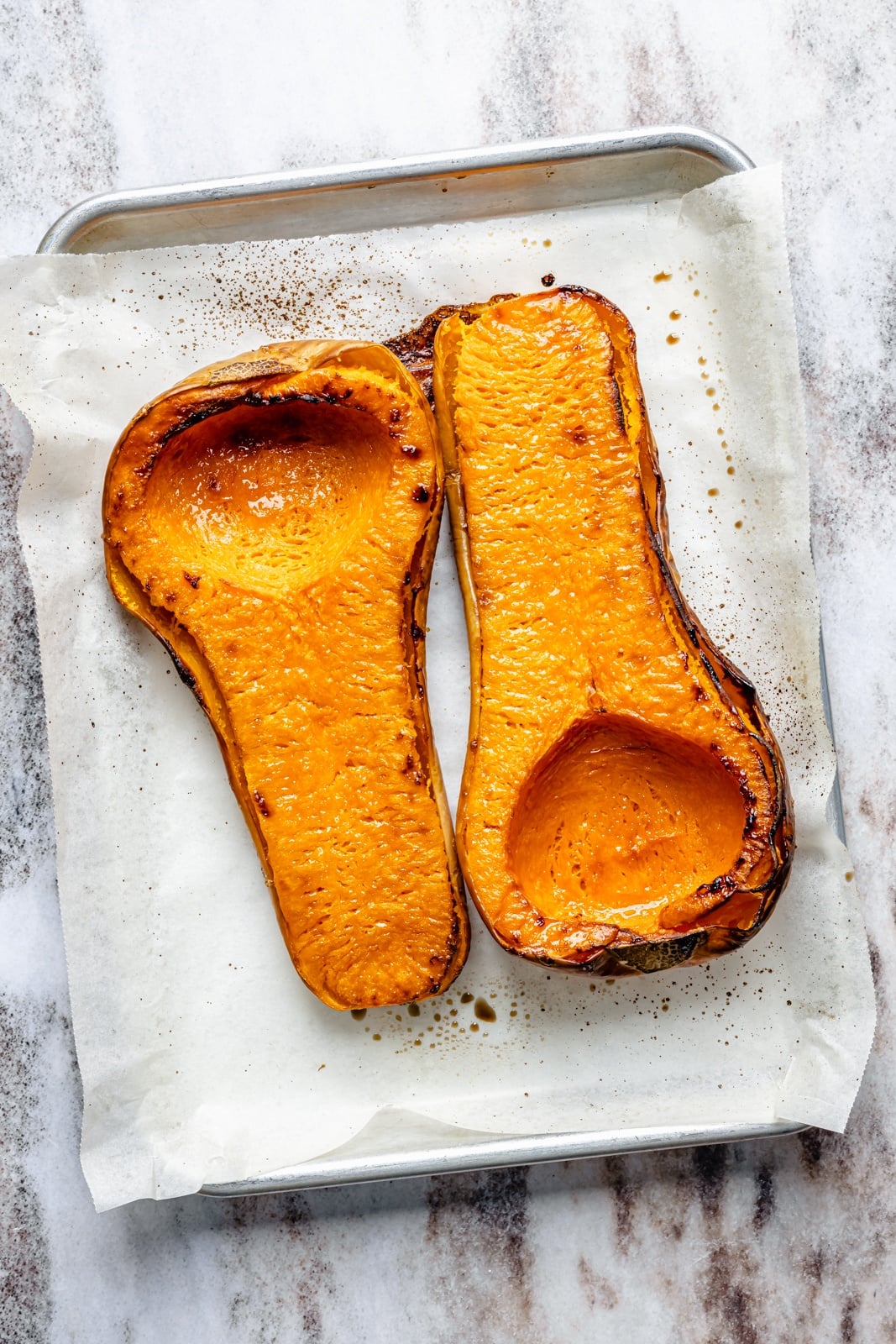 Fluffy butternut squash muffins infused with homemade chai spices, then topped with a simple salted honey glaze that truly takes these to the next level. These fall-inspired, freezer-friendly butternut squash muffins are easy to make and have hints of caramel flavor thanks to a touch of brown butter. Perfect with a cup of coffee! roasted butternut squash on a sheet pan