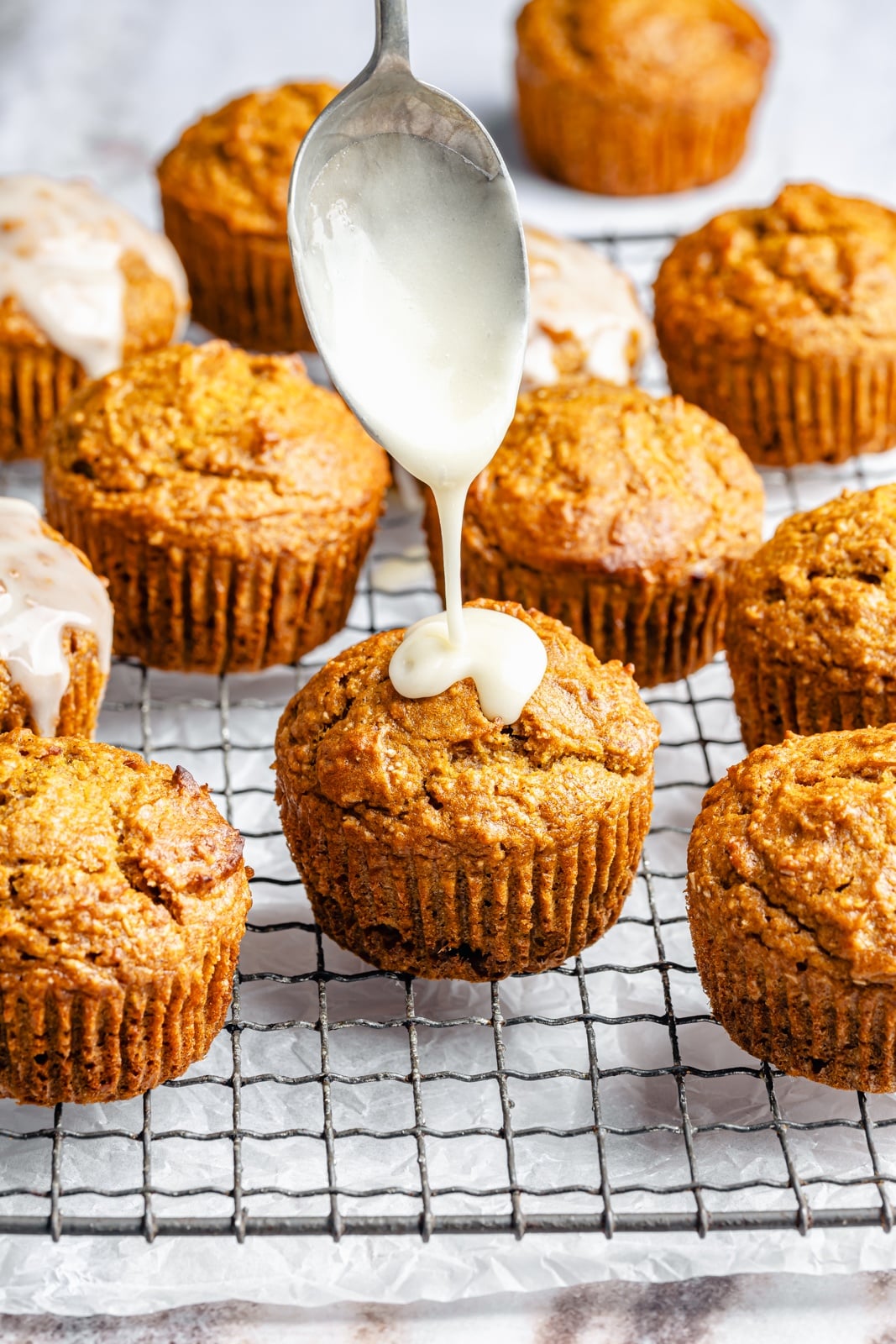 Fluffy butternut squash muffins infused with homemade chai spices, then topped with a simple salted honey glaze that truly takes these to the next level. These fall-inspired, freezer-friendly butternut squash muffins are easy to make and have hints of caramel flavor thanks to a touch of brown butter. Perfect with a cup of coffee! drizzling honey glaze onto butternut squash muffins